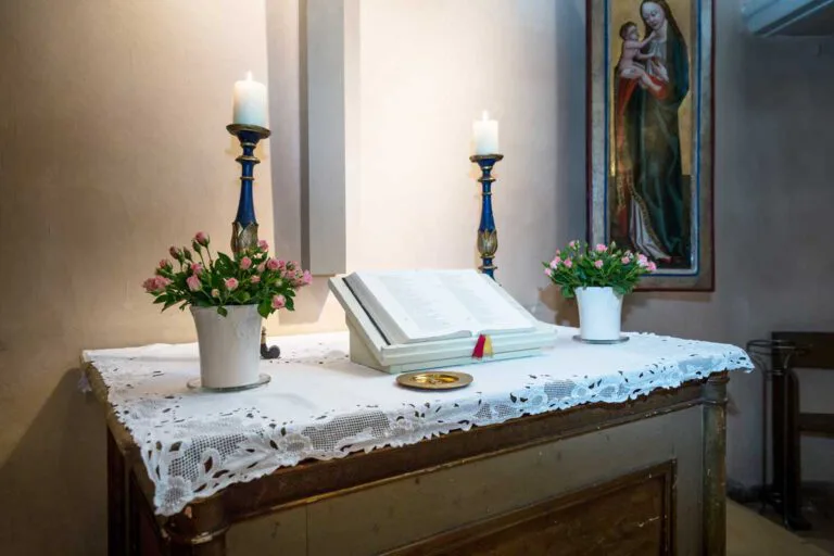 Alte Dorfkirche Zehlendorf Blick auf den Altar. Dort steht ein kleiner goldener Teller, wo die Eheringe für die Trauung liegen. Rechts und links befinden sich jeweils Kerzen und ein Blumenstrauß.