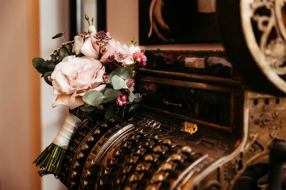 Hochzeitsstrauß und Eheringe dekorativ auf einer alten Kasse fotografiert.