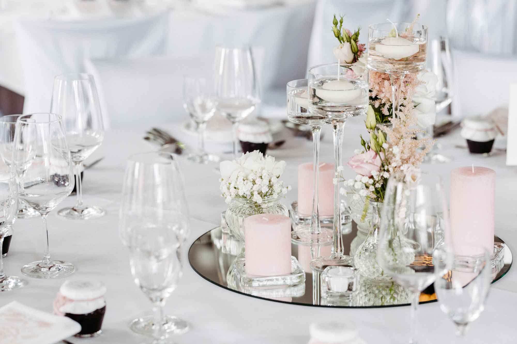 gedeckter Hochzeitstisch mit silbernen Dekotellern mit pastellfarbenen Kerzen