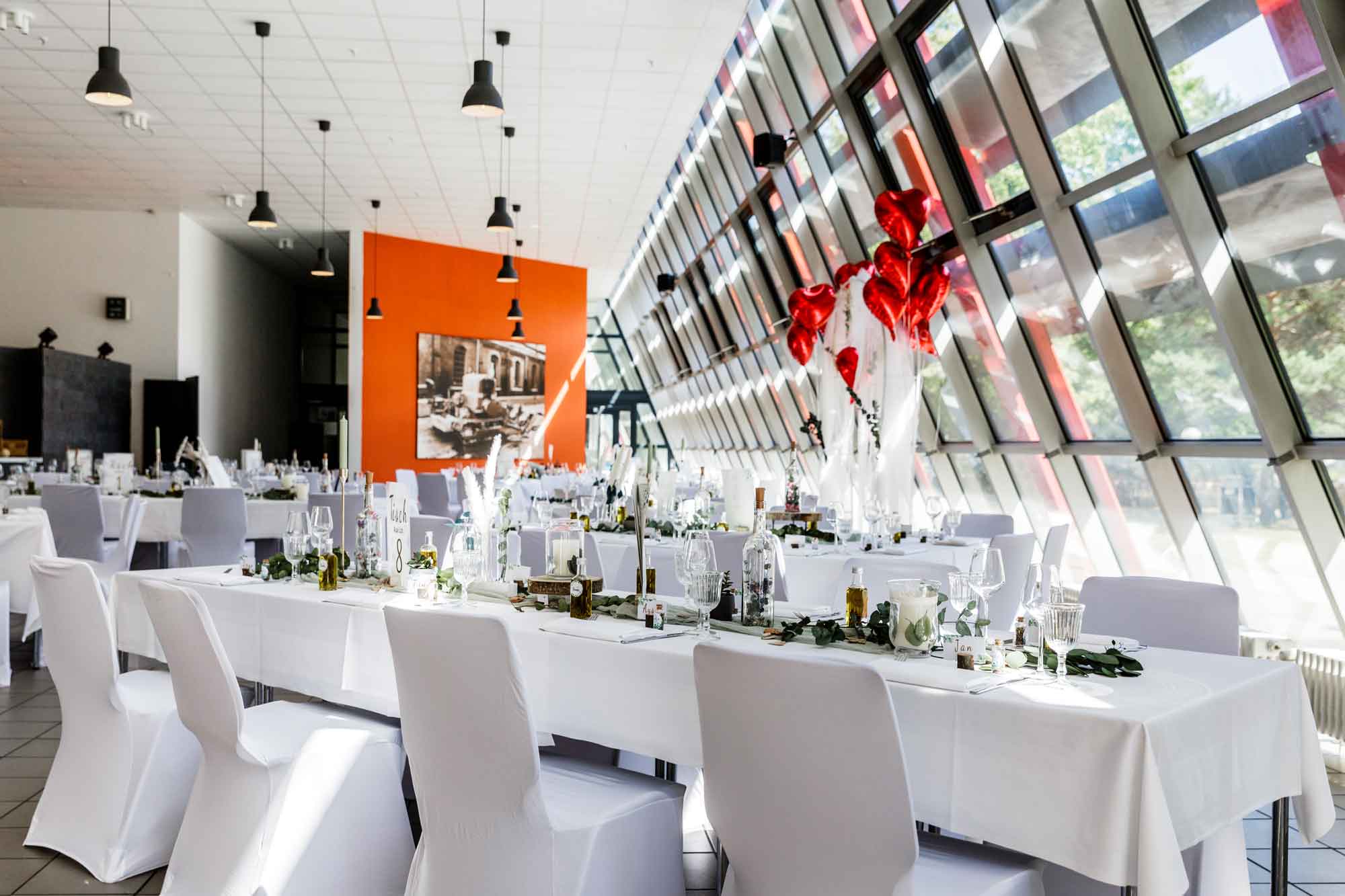 Eventkantine Berlin. Innenansicht mit eingedeckten Hochzeitstischen und Blumendekoration.