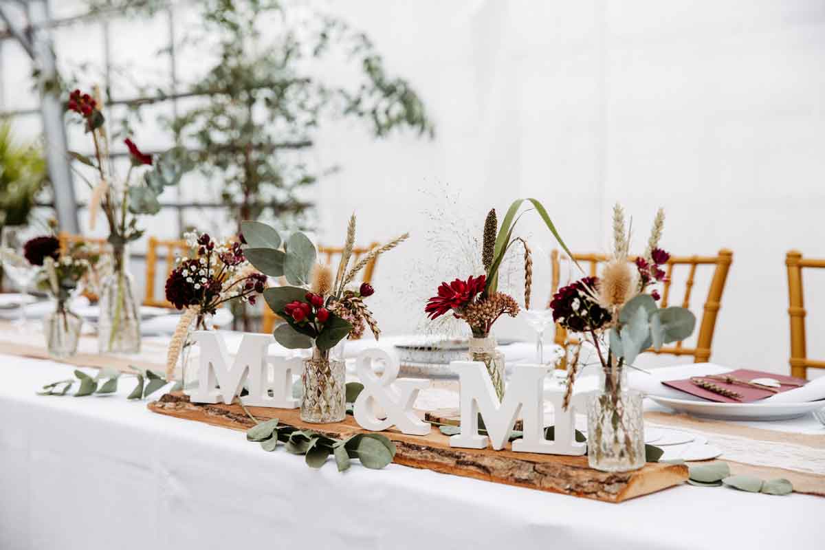 Brauttisch eingedeckt und mit Blumen dekoriert. Mr. & Mrs. als Dekoration.