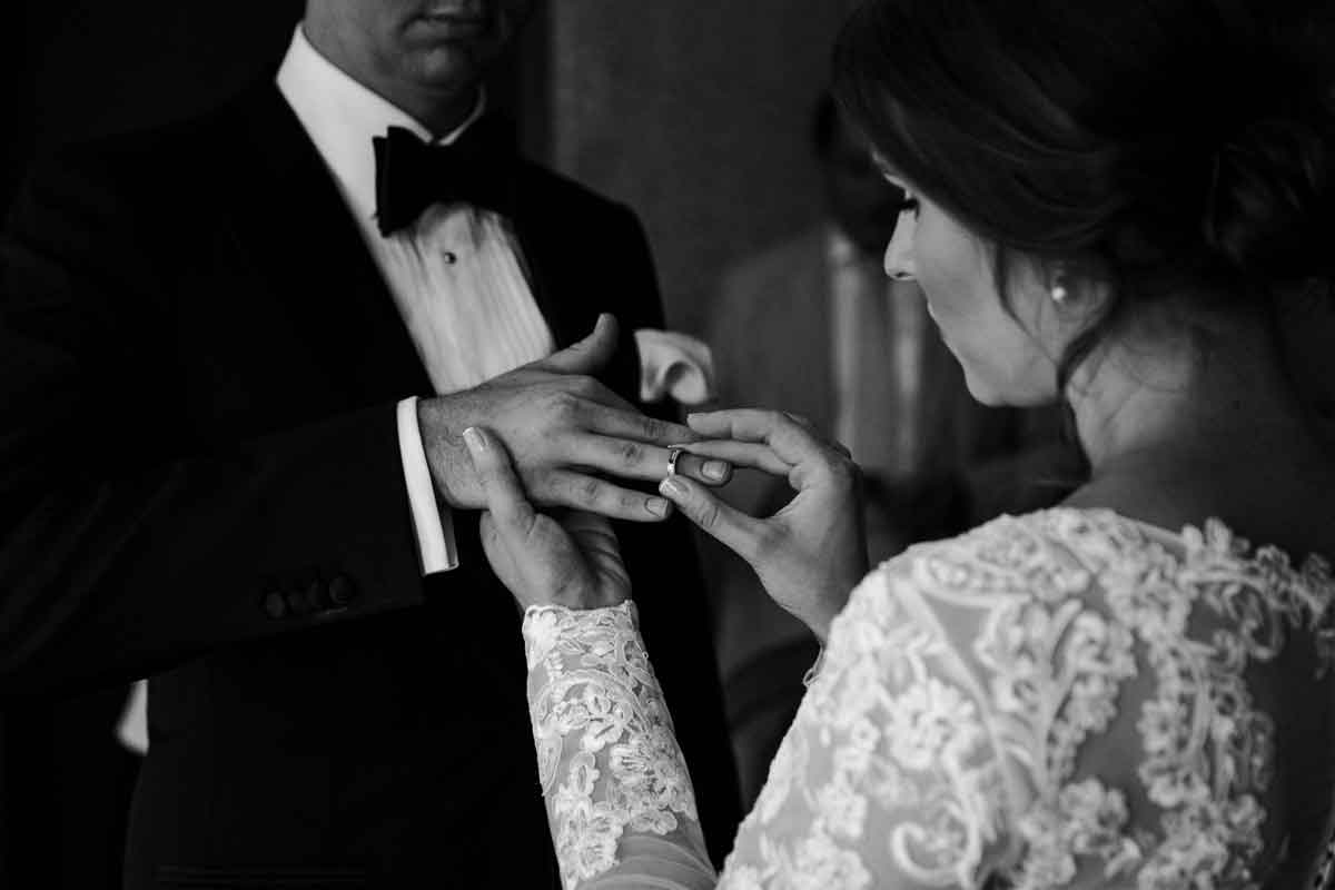 Hochzeit im Standesamt Charlottenburg. Braut steckt dem Bräutigam den Ring auf. Schwarz-weiß Aufnahme. Fokus liegt auf den Händen.