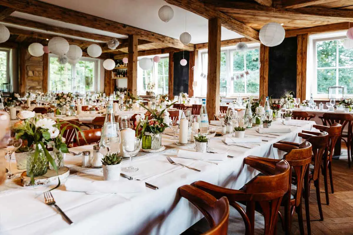 Landleben Potsdam Innenansicht mit direktem Blick auf die eingedeckten Hochzeitstische. Toller Blumenschmuck und schöne Dekoration.