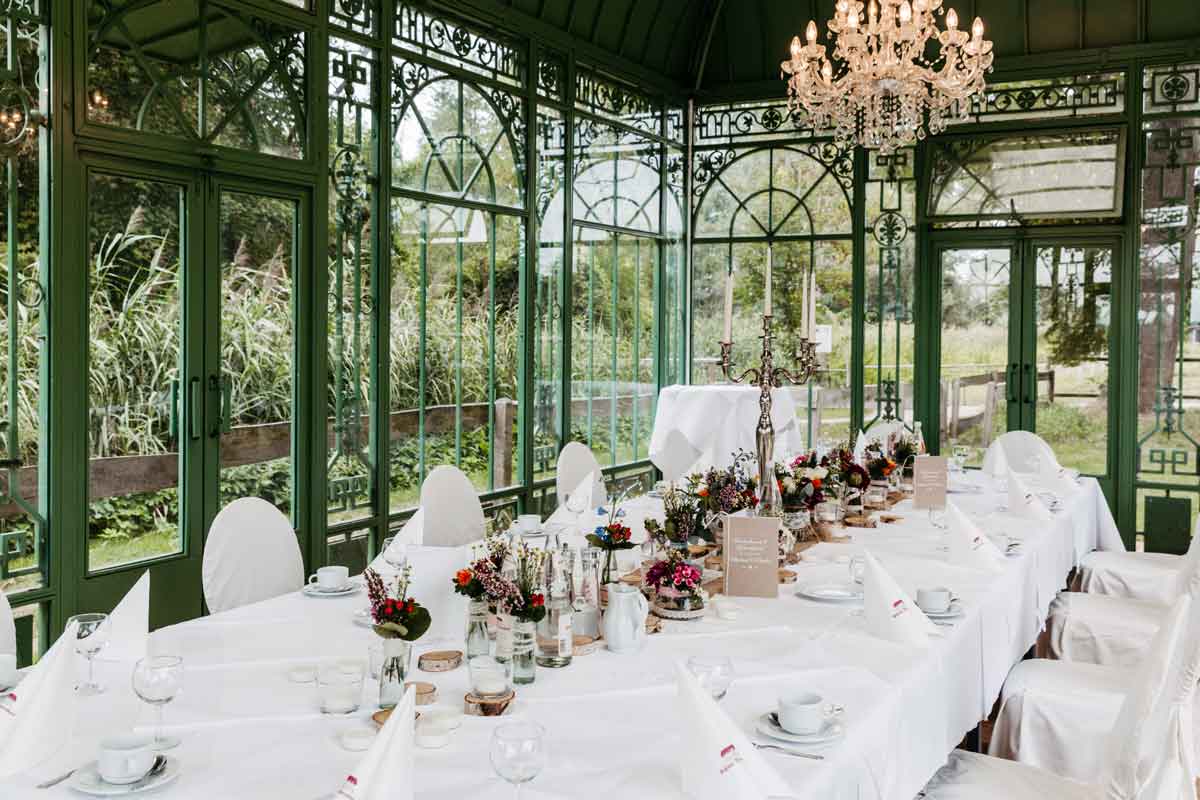 eingedeckter Hochzeitstisch mit Blumenschmuck aufgenommen im Pavillon im Schloss Diedersdorf.