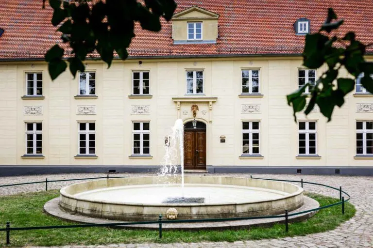 Außenaufnahme Schloss Diedersdorf mit dem Brunnen im Vordergrund.