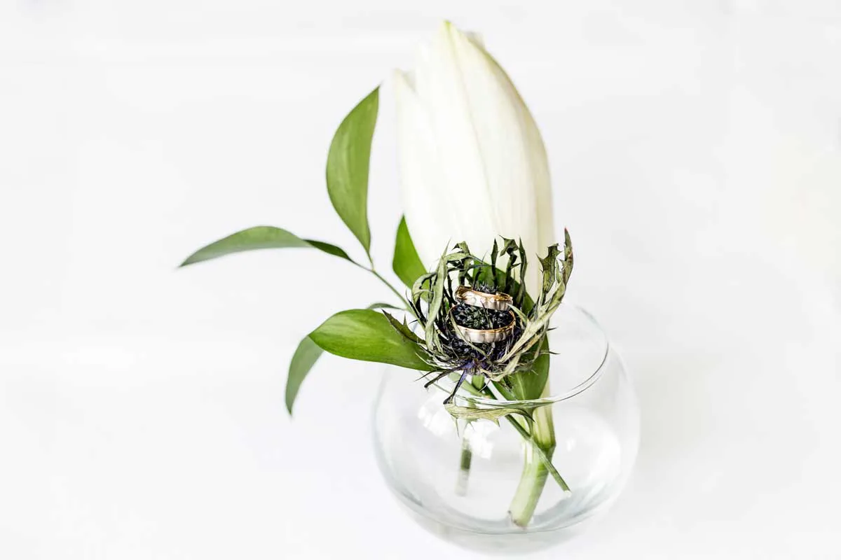 Trauringe auf einer Brombeere mit Blumen in einer Vase
