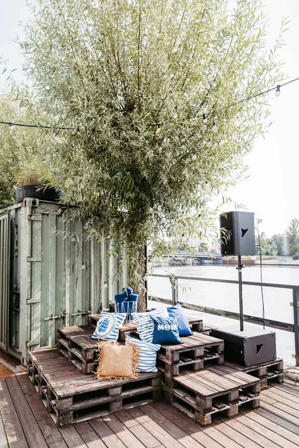 Kissen auf Paletten, die um einen Baum gestellt sind. Hochzeitslocation White Spreelounge Berlin